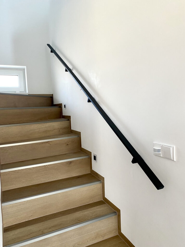 Černé kovové madlo na schodišti.