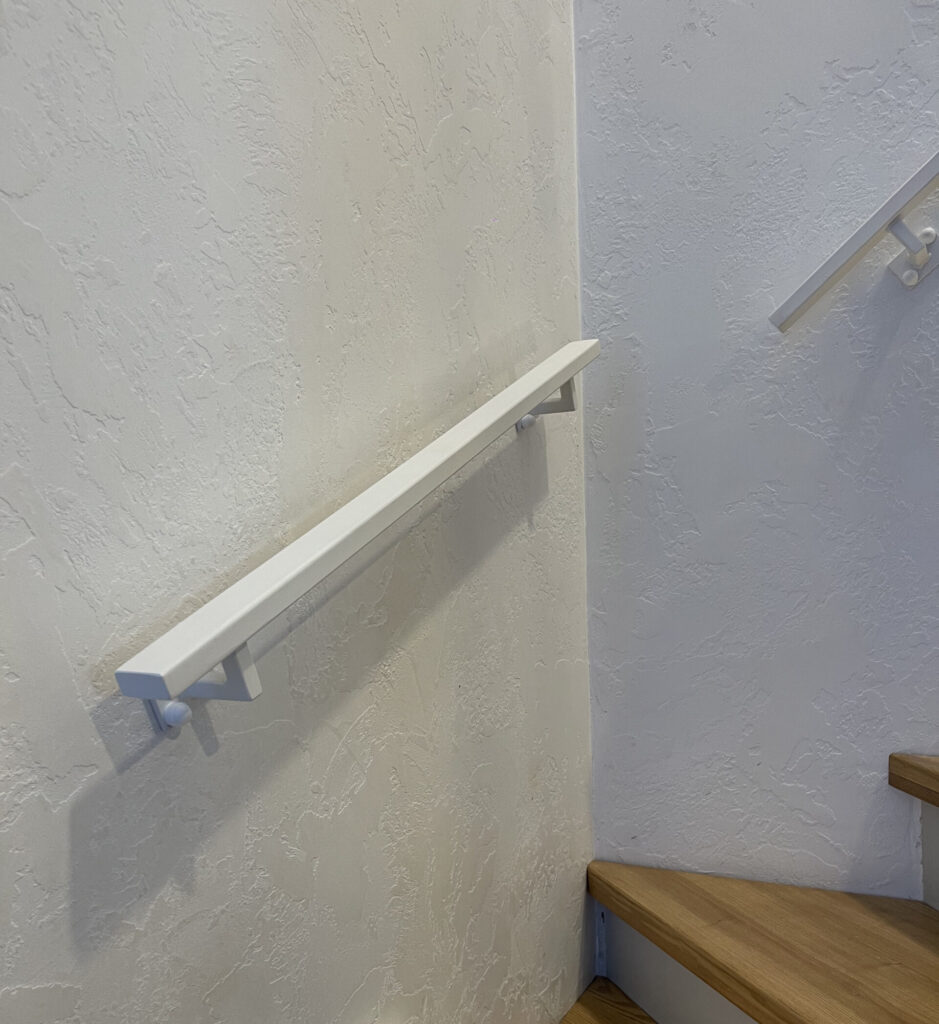 Bílé madlo na schodišti v rodinném domě.